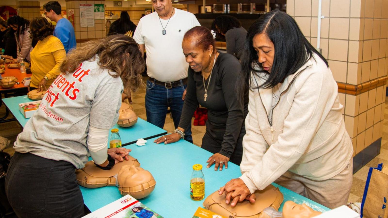 Community members practice chest compressions on CPR manikins during a hands-on training session.