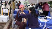 A community member has her blood pressure checked at a ColumbiaDoctors outreach table during an outdoor community event.